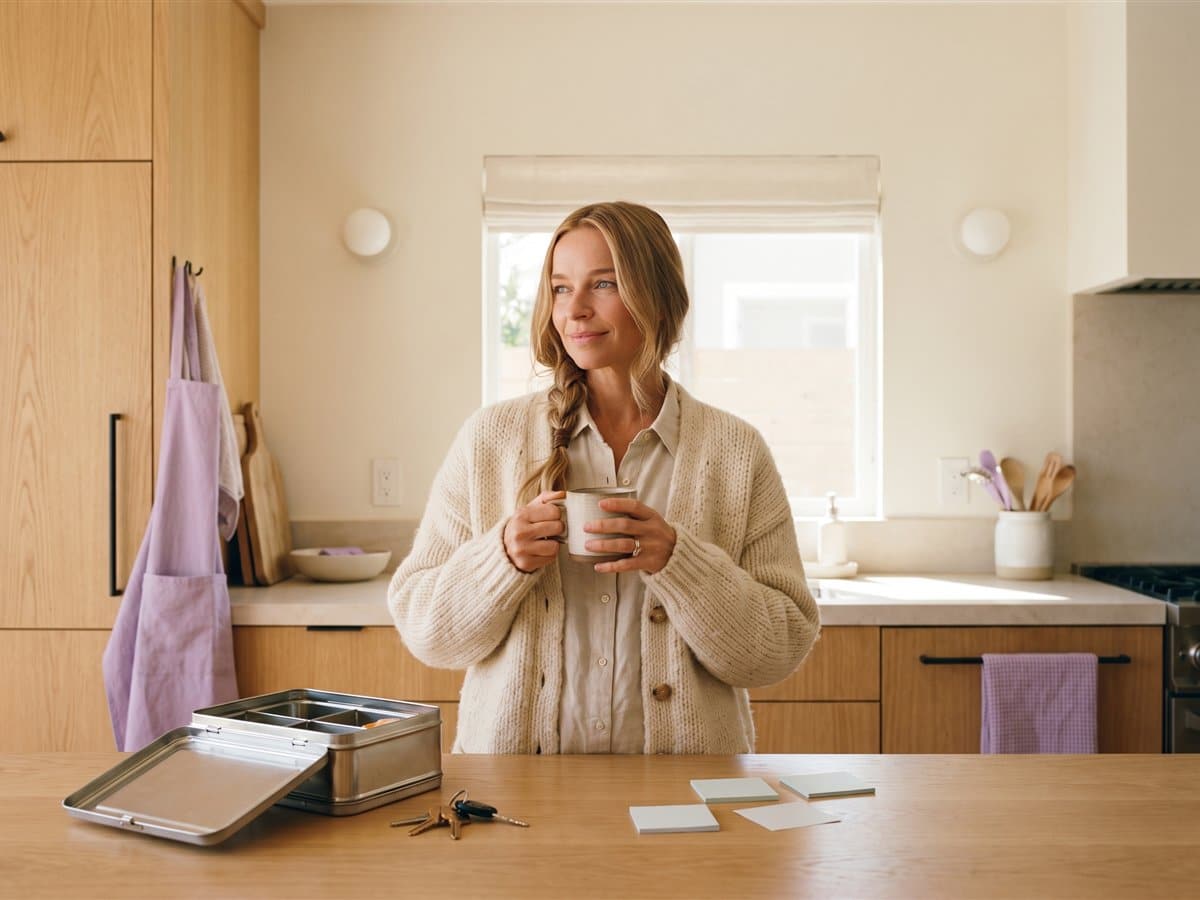 Frau mit Kaffeetasse steht morgens nachdenklich in der Küche